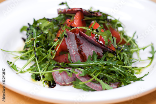 Salad with pieces of marbled beef and arugula on a white plate