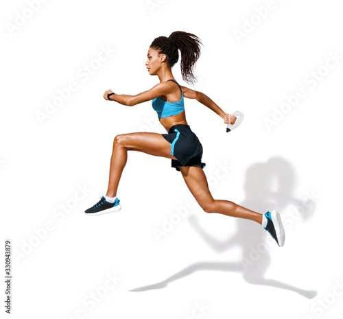 Fototapeta Naklejka Na Ścianę i Meble -  Young fitness girl running with bottle of water. Photo of african american girl in fashionable sportswear on white background. Dynamic movement. Side view. Full length. Sports and healthy lifestyle
