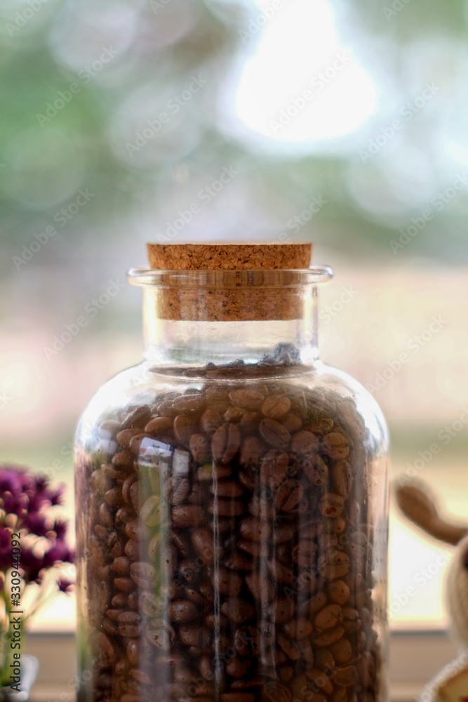 The bottle contains the coffee beans inside with a beautiful bokeh background.