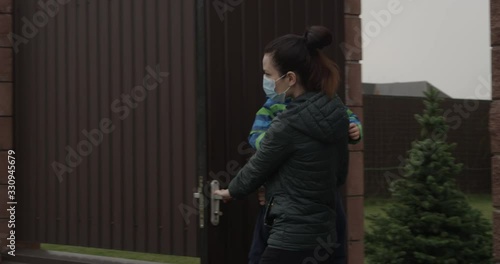 Parent with Child Closing Door wearing Face Masks a Concept of self-isolation and social distancing because of Pandemia of Coronavirus Covid-19 photo