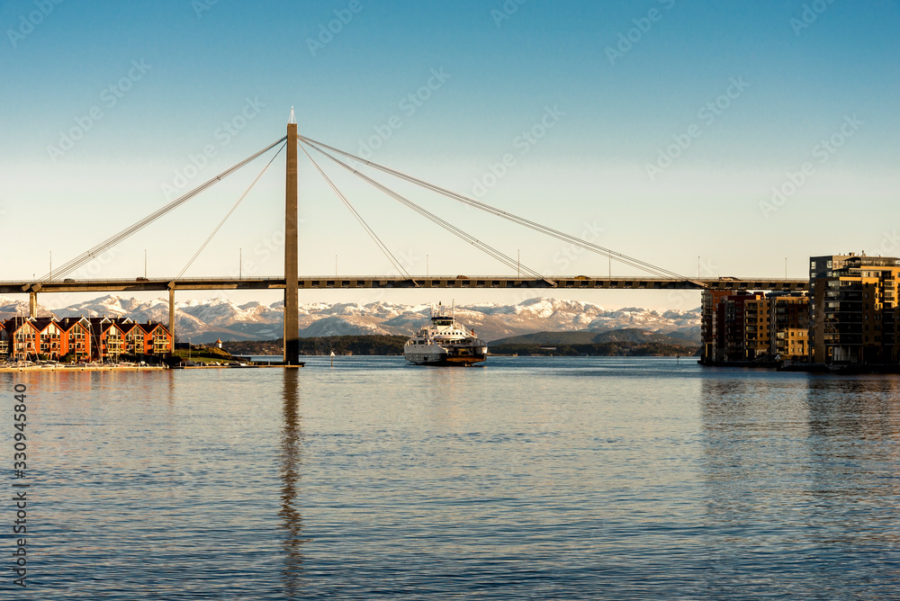 A passenger regular ferry from Stavanger to Tau passes under a city bridge in Stavanger, Norway, December 2017