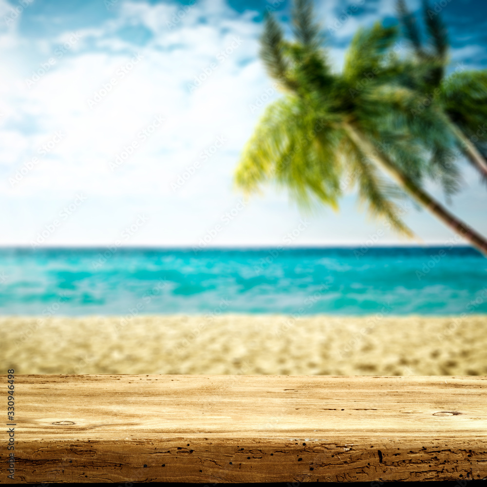 Wooden desk of free space and summer beach background with green palms 