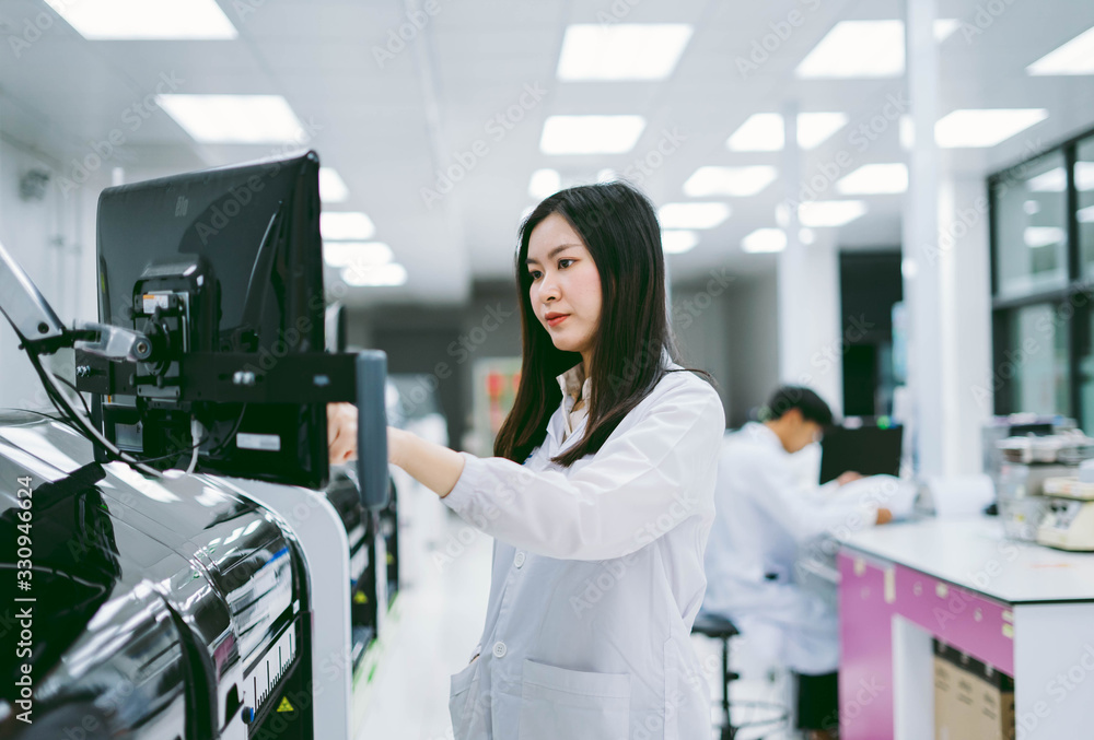 young female scientist working with automation blood analyzer in medical laboratory young female scientist working with automation blood analyzer in medical laboratory