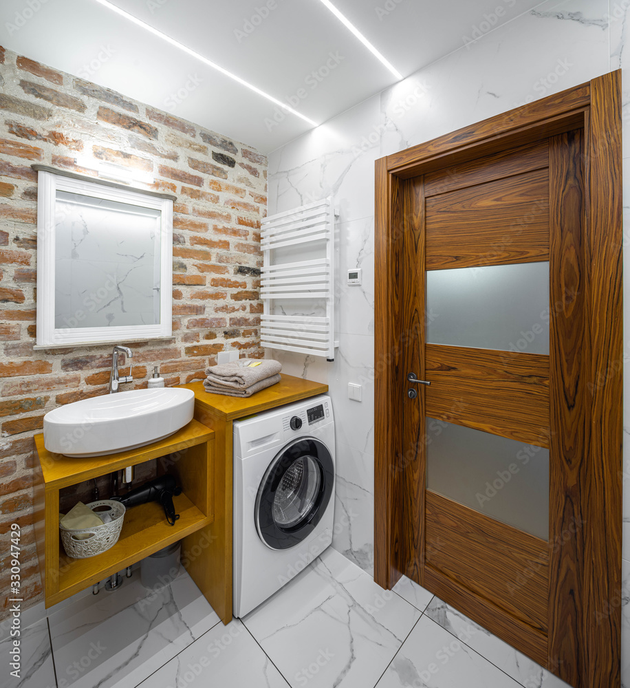 Modern bathroom in apartment. Loft interior. Brick wall. Washing machine.  Wooden door. Stock Photo | Adobe Stock
