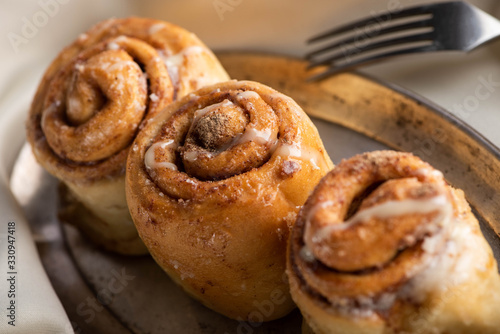 close up view of fresh homemade cinnamon rolls on board on satin cloth with fork