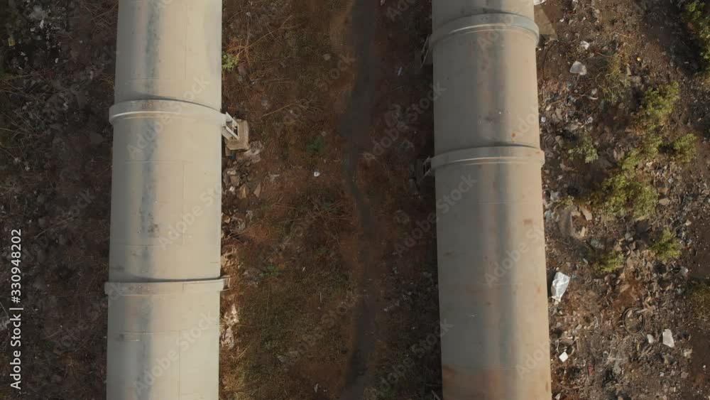 Pan up drone shot from two long pipelines in a mangrove forrest to a large city Pan up drone shot from two long pipelines in a mangrove forrest to a large city