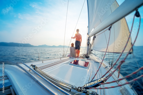 Young couple sailing in the tropical sea at sunset on their yacht. Tilt shift effect applied