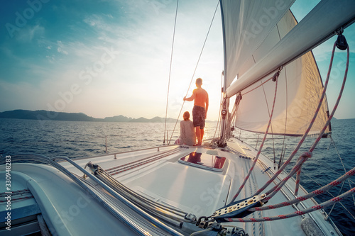 Young couple sailing in the tropical sea at sunset on their yacht