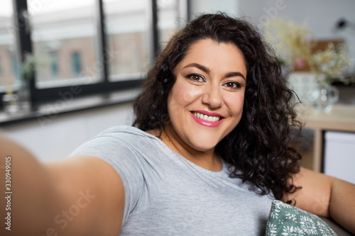 Fotografie people, technology and leisure concept - happy smiling young woman taking selfie