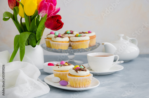 Homemade Easter vanilla cupcakes bird's nest with butter cream, chocolate and candy eggs on a dish. Easter fun food idea for kids. Horizontal orientation. Copy space.