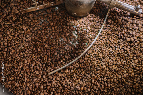 Freshly light roasted arabica coffee beans cooling in a roasters drum. Close up shot.