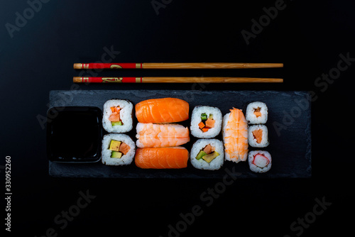 sushi on a black stone accompanied by two chopsticks