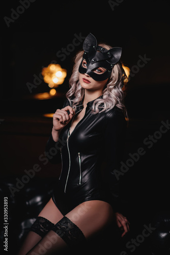 sexy woman in catwoman suit staying on stairs at backyard of building photo