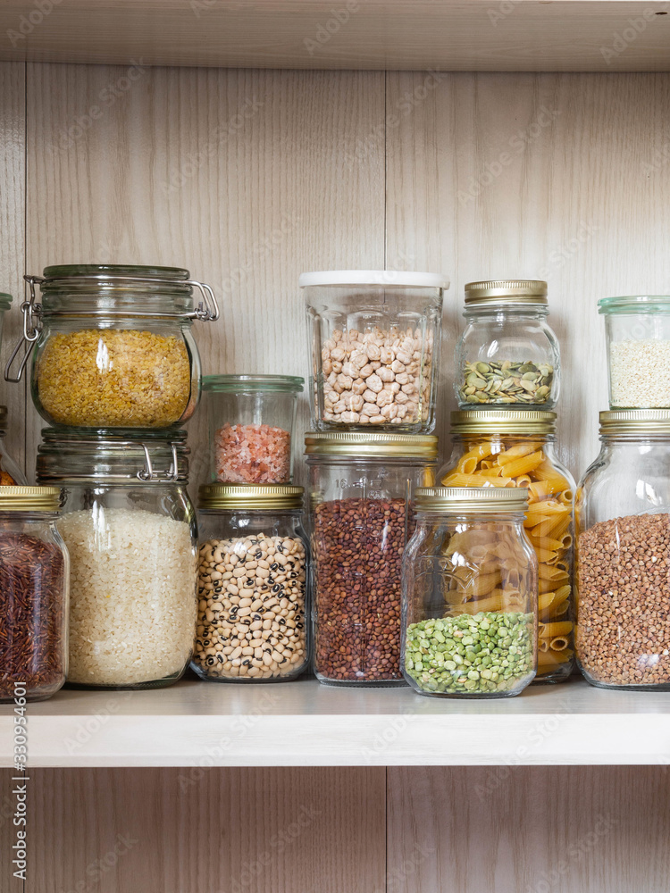 Shelf in the kitchen with various cereals and seeds - peas split, sunflower and pumpkin seeds, beans, rice, pasta, oatmeal, couscous, lentils, bulgur in glass jars Shelf in the kitchen with various cereals and seeds - peas split, sunflower and pumpkin seeds, beans, rice, pasta, oatmeal, couscous, lentils, bulgur in glass jars