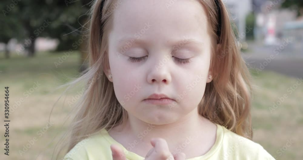 Stock video of a lovely thoughtful child picking her nose in the street. Unfocused blurred background in the park. Stock video of a lovely thoughtful child picking her nose in the street. Unfocused blurred background in the park.