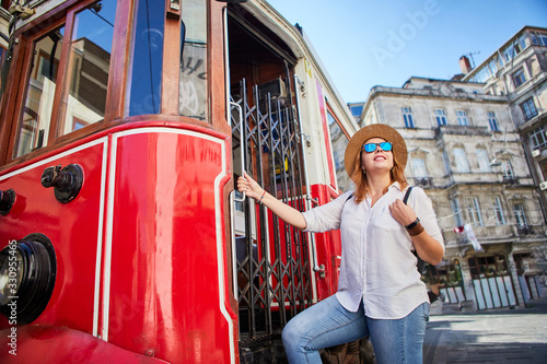 Canvas Print Beautiful young girl tourist in a hat poses in front of tram at popular Istiklal