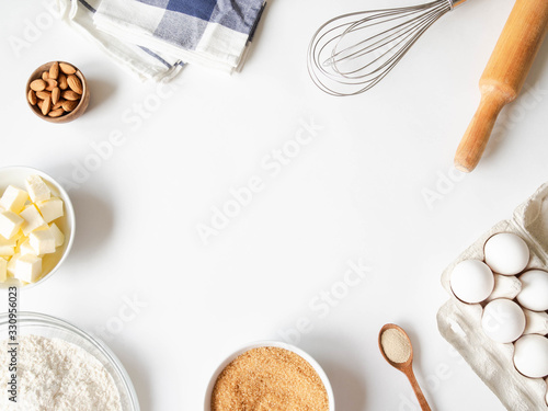 Photo Frame of various baking ingredients - flour, eggs, sugar, butter, dry yeast, nuts and kitchen utensils on white background