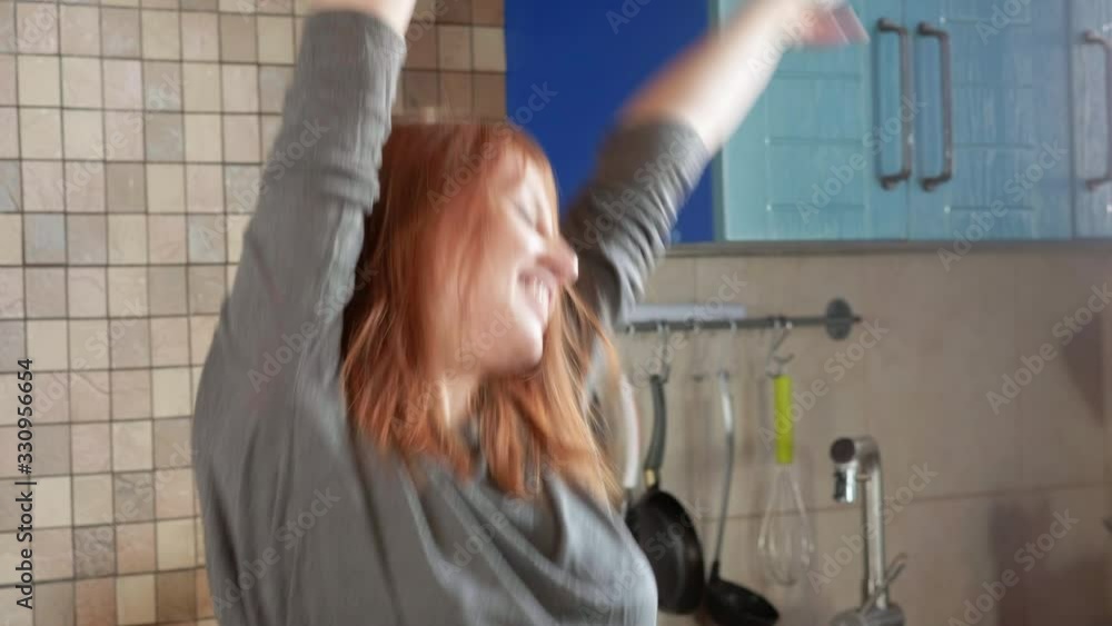 Attractive girl with red hair drinks morning coffee in the home kitchen. Dancing fun at home. Redhead woman dancing in the kitchen. Enjoying life alone Attractive girl with red hair drinks morning coffee in the home kitchen. Dancing fun at home. Redhead woman dancing in the kitchen. Enjoying life alone