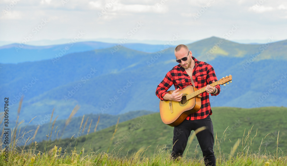 Naklejka premium Acoustic music. Musician hiker find inspiration in mountains. Keep calm and play guitar. Man with guitar on top of mountain. Music for soul. Playing music. Sound of freedom. In unison with nature