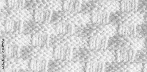 Texture pattern knitting with acrylic thread. Manual work with knitting needles, white background of wool.