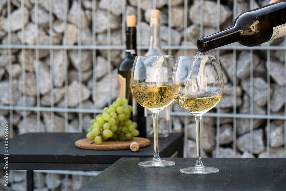 Obraz premium Waiter pouring white wine on outdoor cafe terrace in sunny summer day