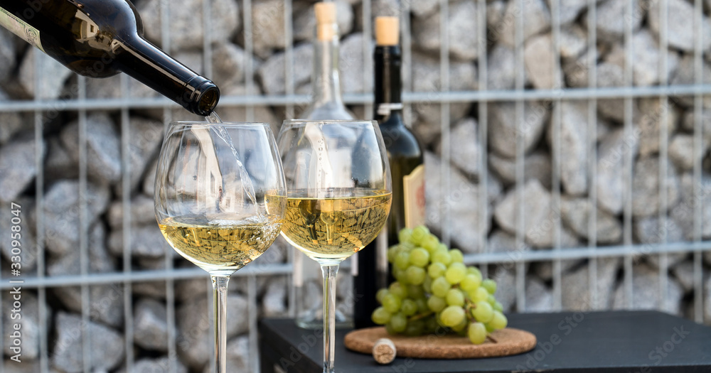 Obraz premium Waiter pouring white wine on outdoor cafe terrace in sunny summer day