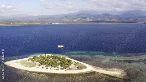 Tourist boat anchored next to Pulau Bedil, a tiny Indonesian beautiful island off the coat of Lombok, Aerial view. photo