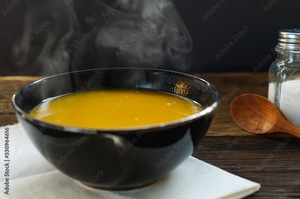 Steaming of hot pumkin soup in white bowl served on wooden table ready to eat. Hot food is good for healthy Steaming of hot pumkin soup in white bowl served on wooden table ready to eat. Hot food is good for healthy