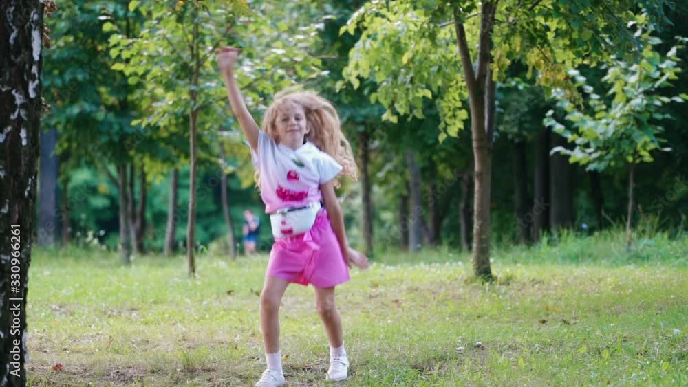 Little kid dancing in green park. Outdoor portrait of happy girl in park Little kid dancing in green park. Outdoor portrait of happy girl in park