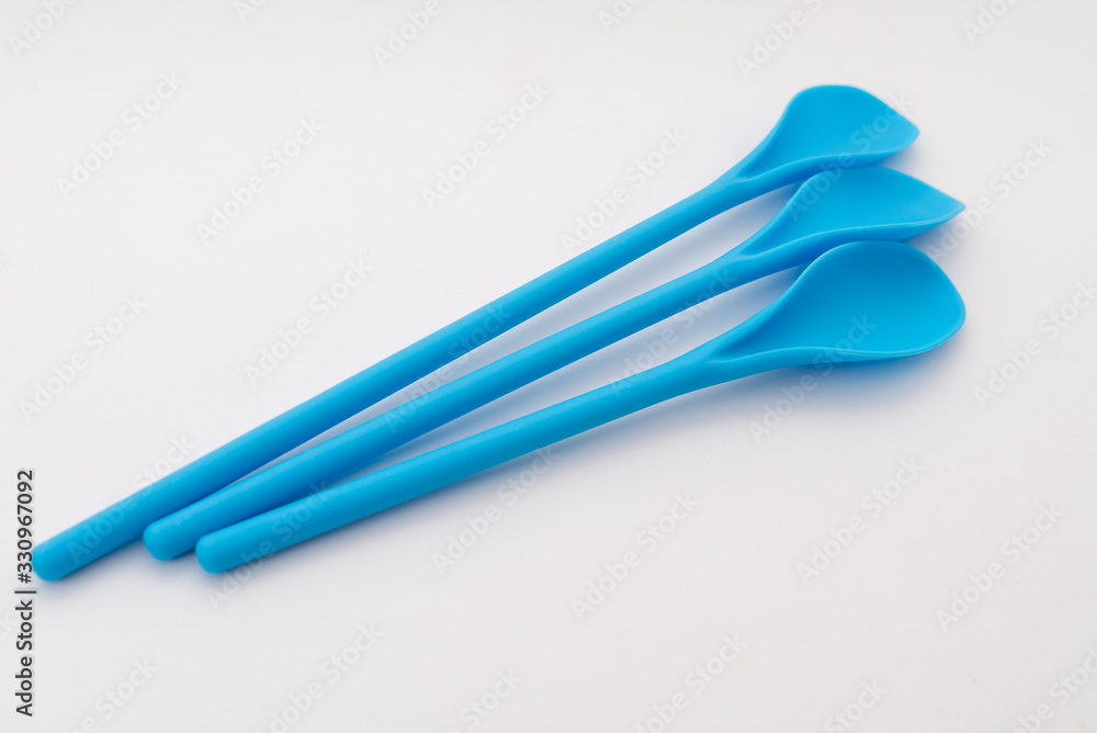 three blue kitchen plastic spoons on white background three blue kitchen plastic spoons on white background