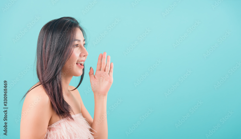 woman standing smiling profile shouting and holding hand near her open mouth woman standing smiling profile shouting and holding hand near her open mouth