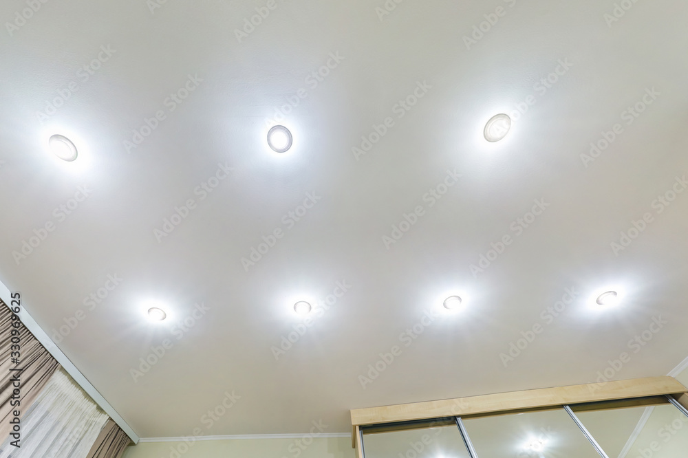 suspended ceiling with halogen spots lamps and drywall construction in empty room in apartment or house. Stretch ceiling white and complex shape. suspended ceiling with halogen spots lamps and drywall construction in empty room in apartment or house. Stretch ceiling white and complex shape.
