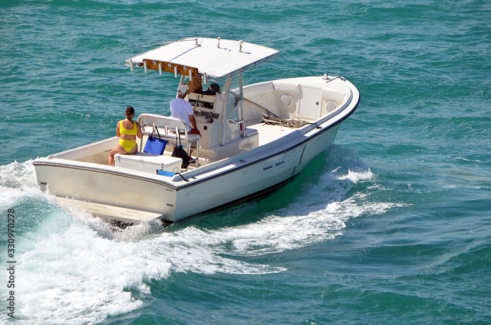 Open white fishing boat with center console on the Florida Intra-Coastal Waterway off Miami Beach.