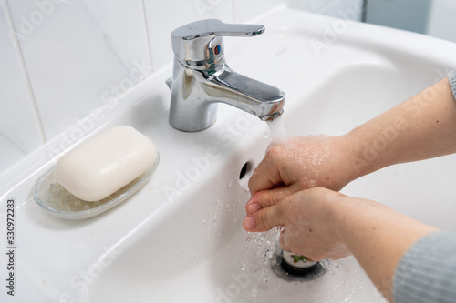 Two hands washing in a white sink