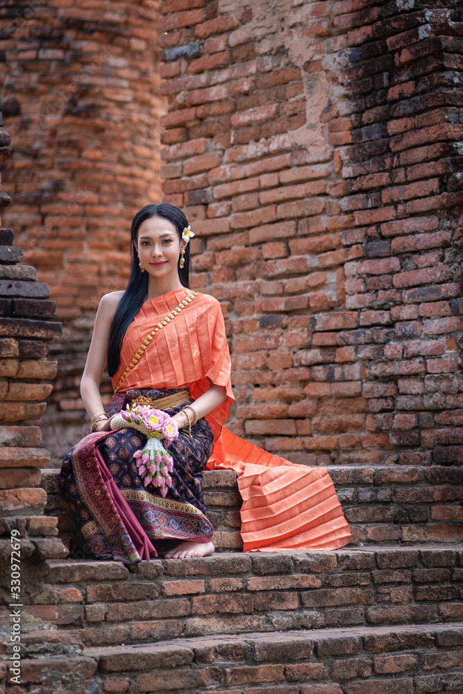 Pretty Asian women with beautiful garland in here hand and wearing traditional Thai dress costume according Thai culture at Ayutthaya, Thailand
