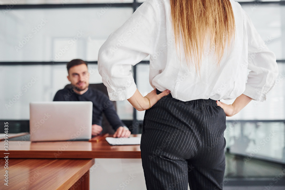 Woman and man in formal clothes working together indoors in the office by table Woman and man in formal clothes working together indoors in the office by table