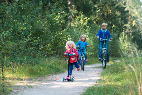 happy active kids on bike and scooter ride in nature