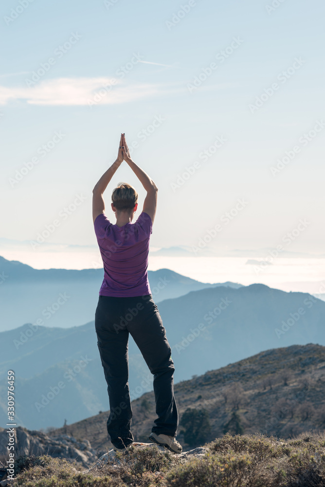 Hiker woman doing yoga on top of the mountain. Hiker woman doing yoga on top of the mountain.