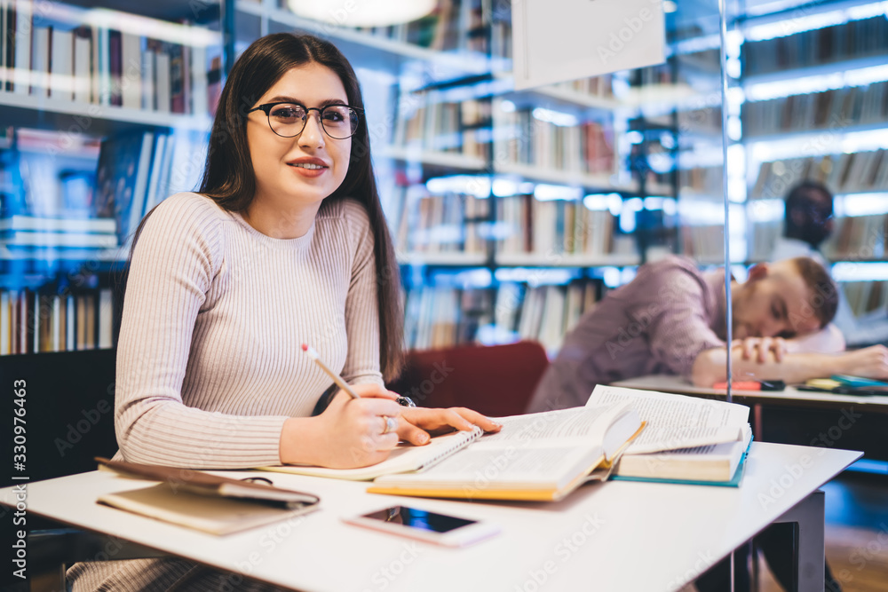 Happy woman in glasses learning in library Happy woman in glasses learning in library
