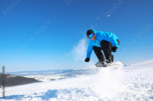 Man snowboarding on snowy hill, space for text. Winter vacation
