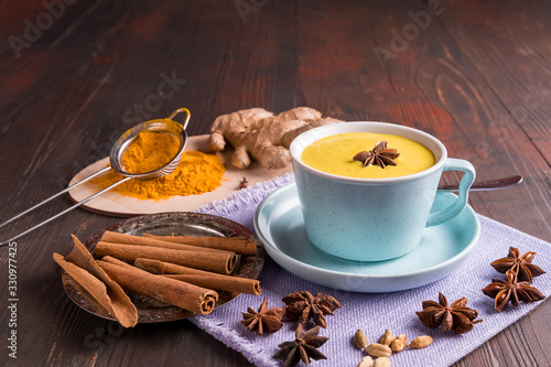 Golden latte milk tea made with turmeric with spices on wooden background.