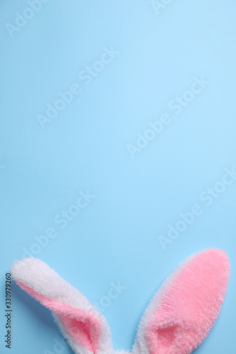 Decorative bunny ears and space for text on light blue background, flat lay. Easter holiday