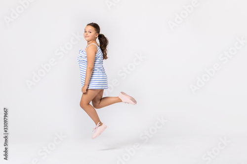 Cute teenage girl jumping in the empty room, copy space on the white wall