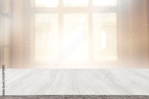 image of wooden table in front of abstract blurred window light background