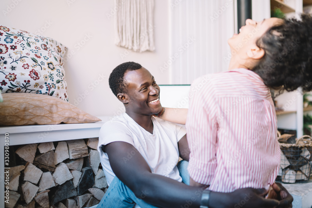 Obraz premium Diverse couple hugging and laughing at home