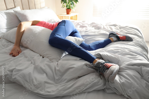 Lazy young woman sleeping on bed instead of morning training