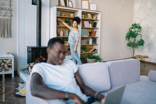 Ethnic woman choosing book and looking at camera