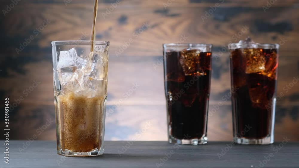 Pouring full glass drink cola with foam, sweet drink with ice and bubbles Pouring full glass drink cola with foam, sweet drink with ice and bubbles