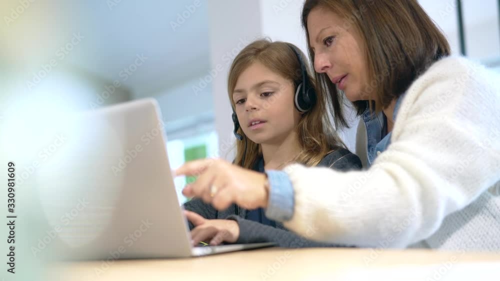 Mother and kid at home doing school teaching online Mother and kid at home doing school teaching online