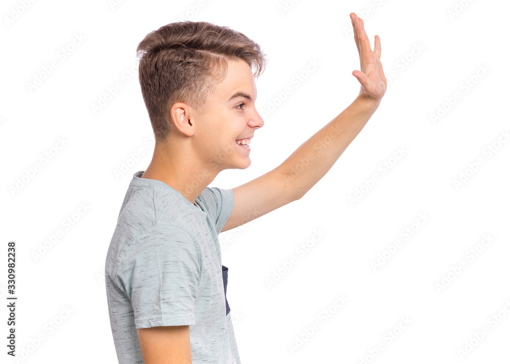 Portrait of happy teen boy making greeting gesture with palm - side view. Teenager student Back to school. Caucasian cute smiling child - profile, isolated on white background. Portrait of happy teen boy making greeting gesture with palm - side view. Teenager student Back to school. Caucasian cute smiling child - profile, isolated on white background.
